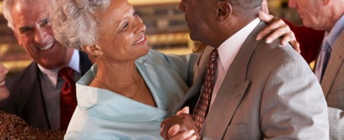 elderly African-American couple smiling and dancing